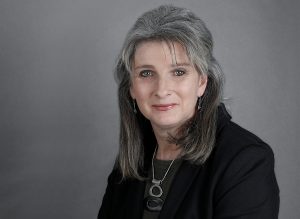 Landscape view of Caroline Vasica. Wearing black clothing with a grey background.